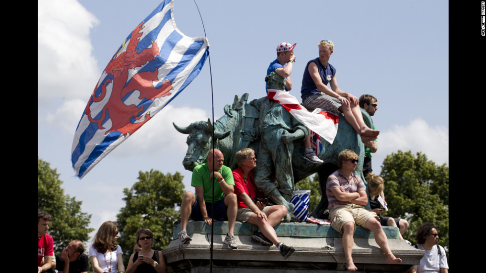 Cycling fans sit on a bronze statue in the town of Liege, Belgium, to get a glimpse of the individual time trial on Saturday.