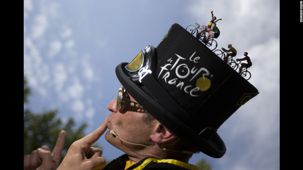 A performer wearing a hat decorated with toy cyclists poses for spectators on Saturday.