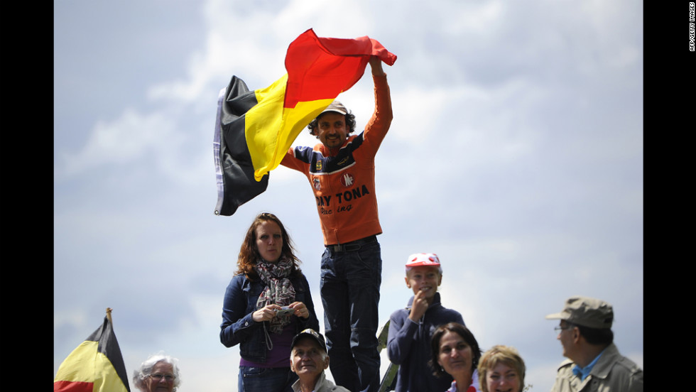 A spectator waves the Belgian flag as fans wait for riders to pass along the Stage 1 route on Sunday.