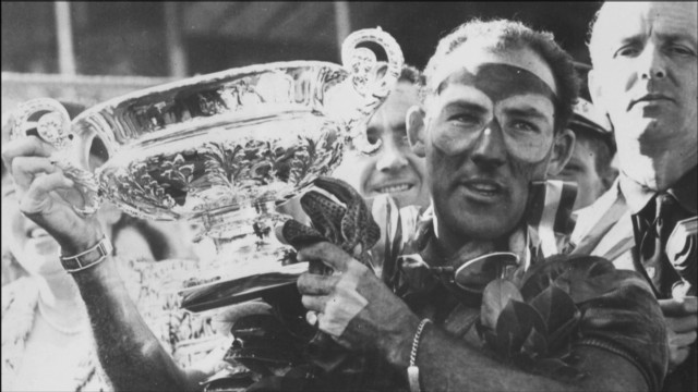 Stirling Moss lifts the trophy at the British Grand Prix in 1955.
