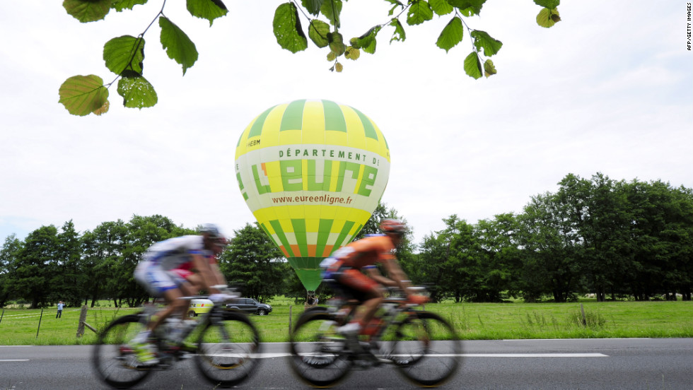 Riders roll past a hot-air balloon sitting in a field along Thursday&#39;s course.