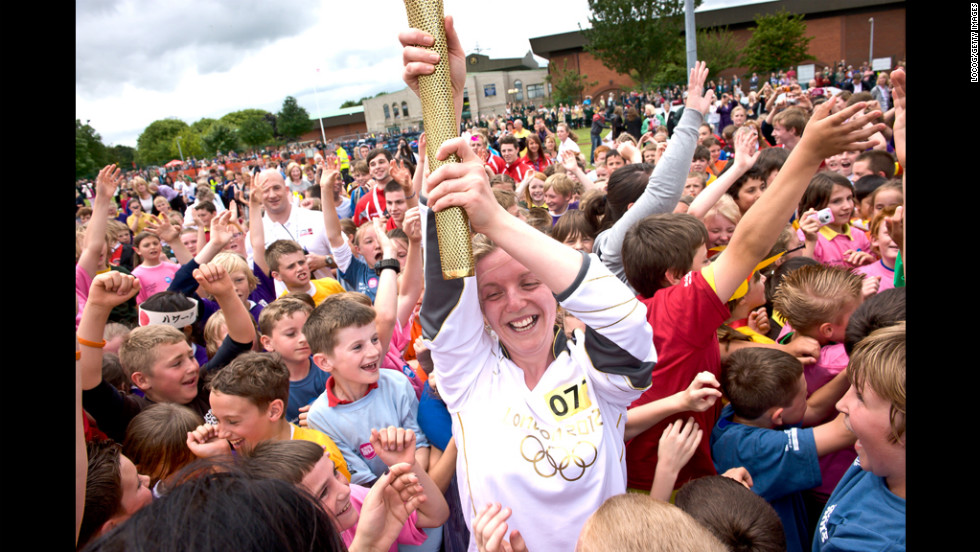 Lauren Reeder, a teaching assistant, is surrounded by local children while carrying the torch in King&#39;s Lynn, England, on July 4.