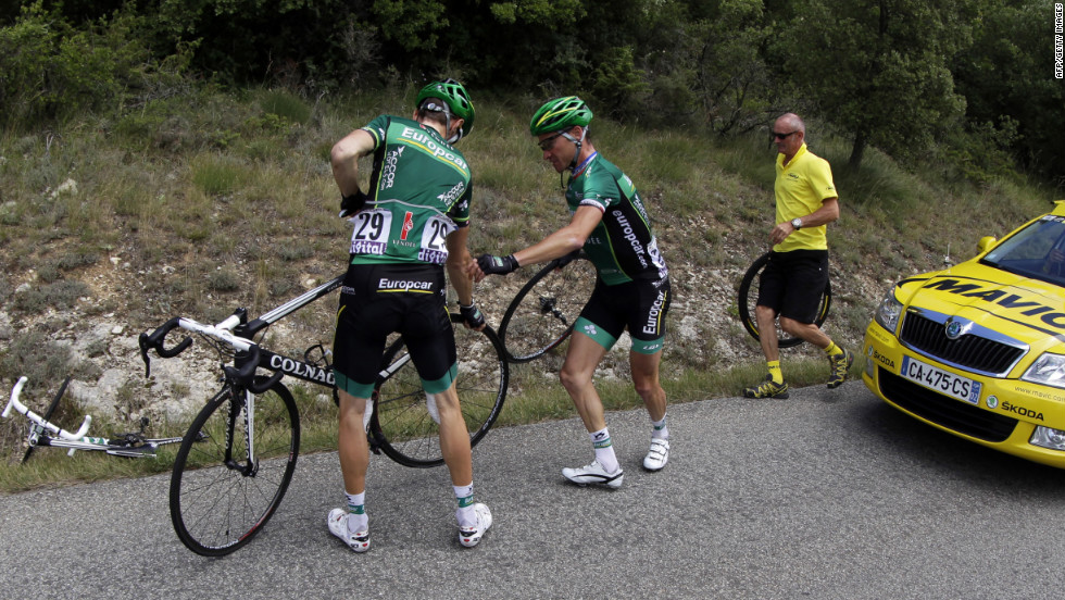 France&#39;s Thomas Voeckler, center, helps teammate Pierre Rolland of France, left, change a wheel during the race Sunday. Around 30 punctured tires were reported near the top of the last major climb, apparently caused by tacks thrown on the course by spectators.