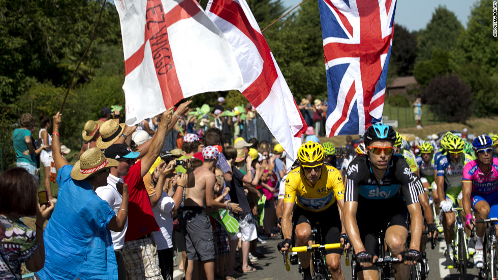 Fans applaud Great Britain&#39;s Bradley Wiggins, here in the yellow jersey, as he makes his way up a climb in the main group Monday.