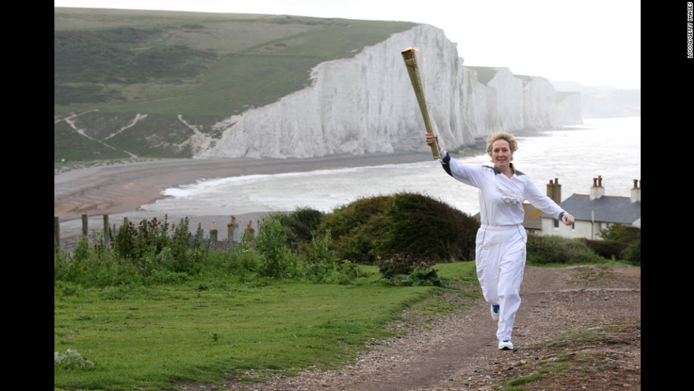 Torchbearer Kathy Gore of Uckfield runs with the Olympic flame at Seaford Head in front of the Seven Sisters cliffs in East Sussex on Tuesday, July 17.