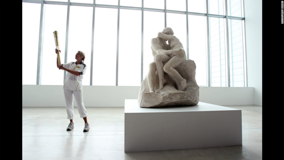 British artist Tracey Emin holds the Olympic flame inside the Turner Contemporary Gallery in Margate alongside &quot;The Kiss&quot; sculpture by Rodin on Thursday, July 19. 