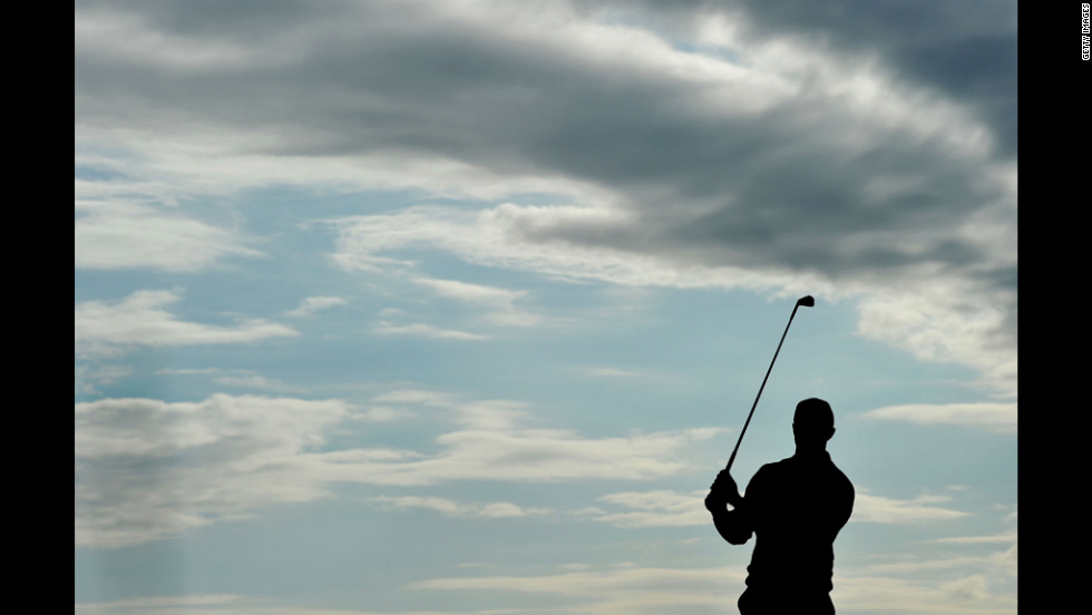 Woods takes practice swings at No. 15 under gray wisps of clouds during Friday&#39;s round.