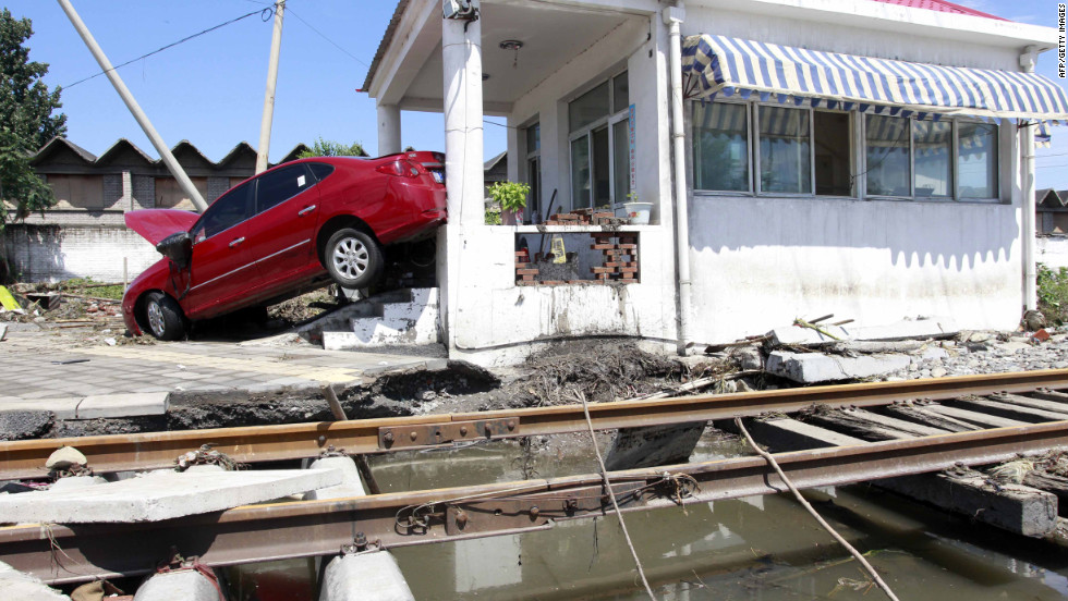 A  flood-swept car is lodged against a building at a railway crossing in Beijing on Saturday, July 21.