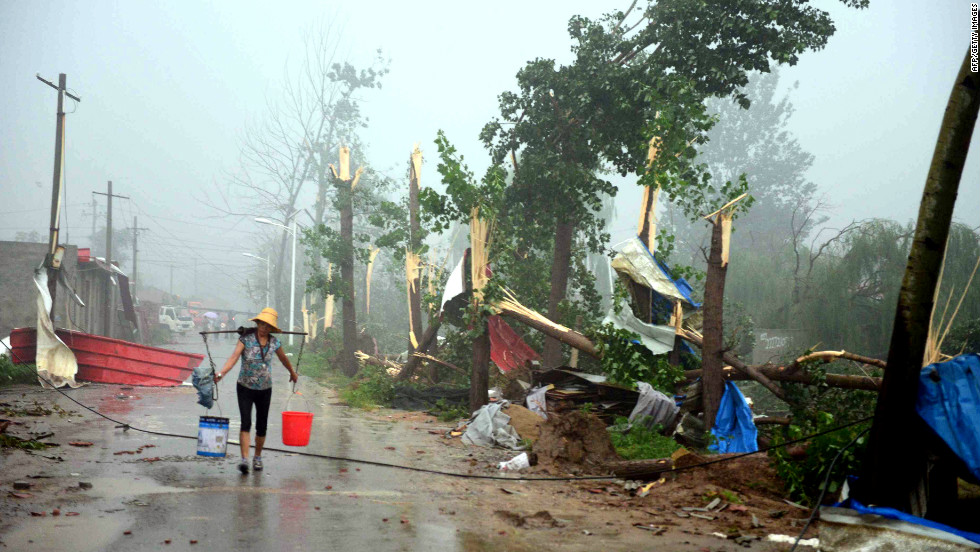 A Beijing resident carrying buckets of water as she makes her way home through a storm on Saturday, July 21.