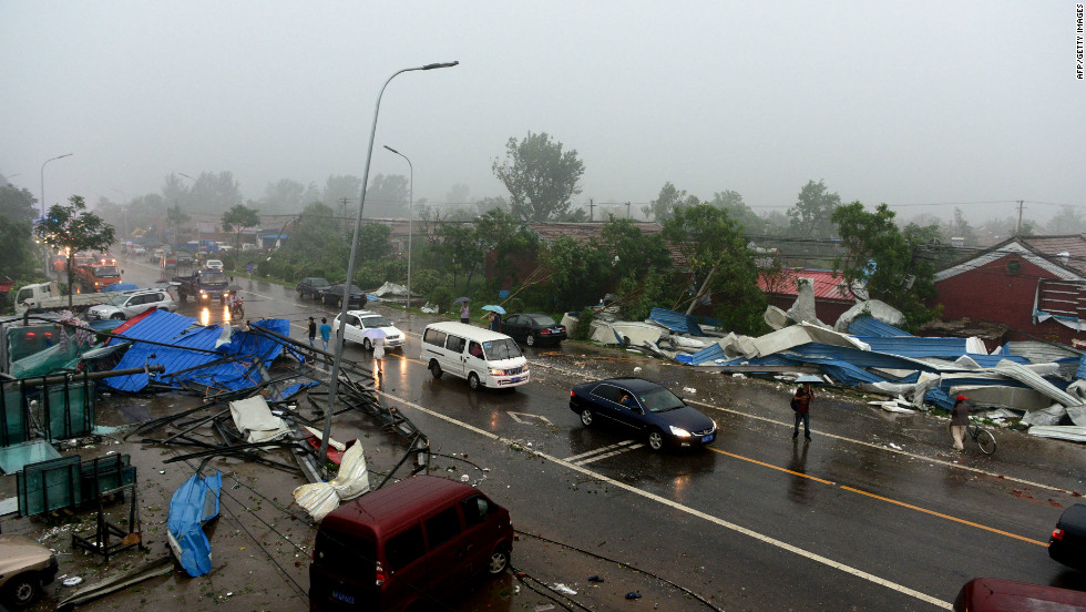 Commuters make their way home through roadside debris as a storm hits Beijing, July 21.