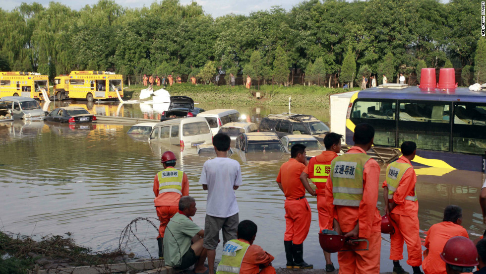Emergency services personnel try to retrieve damaged vehicles submerged in a flooded carpark after a storm hit Beijing, July 22.