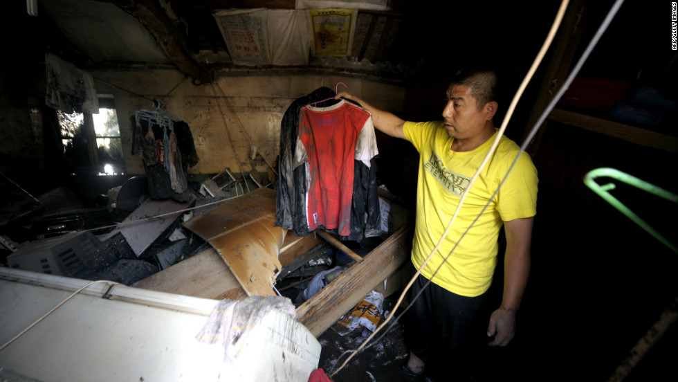 A resident checks his damaged home after a storm hit the city, July 22.