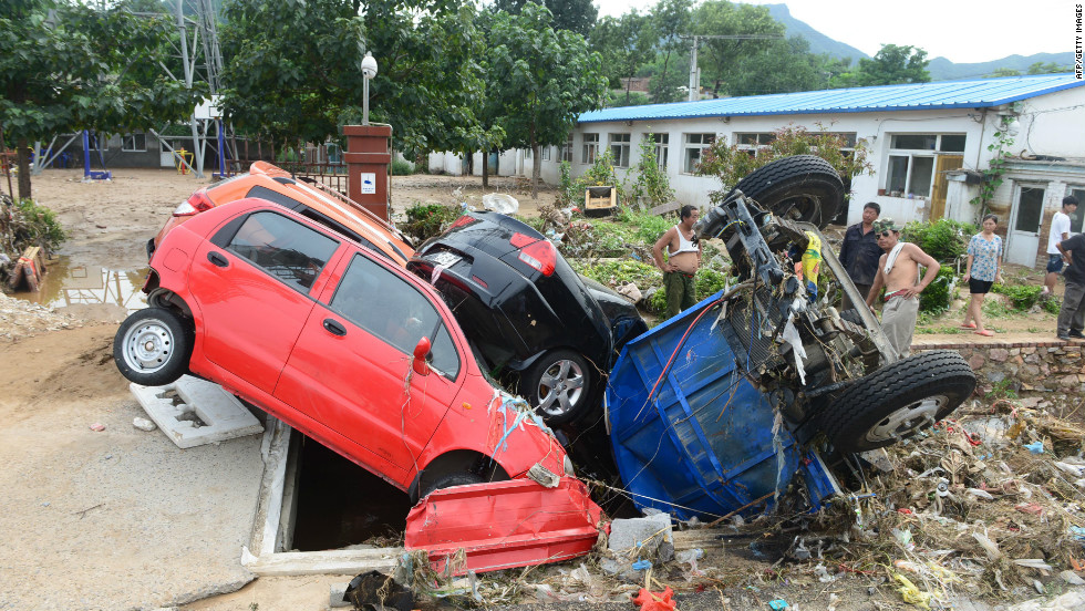 As the floodwater cleared, the damage became clearer. These cars are wedged in a hole in Beijing, July 23, 2012.