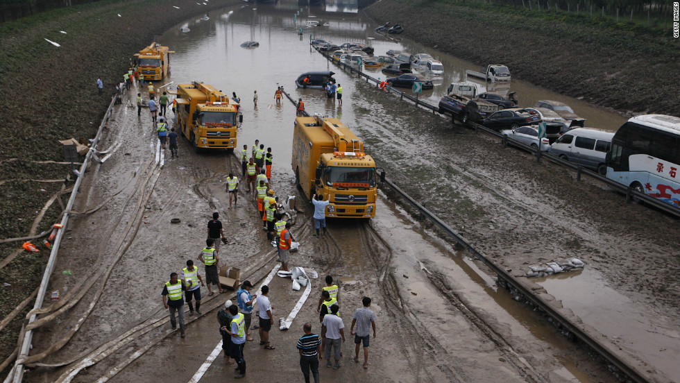 Municipal workers try to clear water on a section of the Beijing-Hong Kong-Macau expressway, where more than 80 cars were submerged on Monday, July 23, in Beijing.