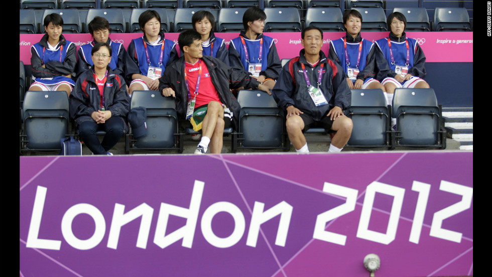 North Korean soccer coach Gun Sin Ui, at center in red shirt, waits for his team&#39;s match to begin at Hampden Park in Glasgow, Scotland, on Wednesday, July 25. The first-round match against Colombia was delayed. 
