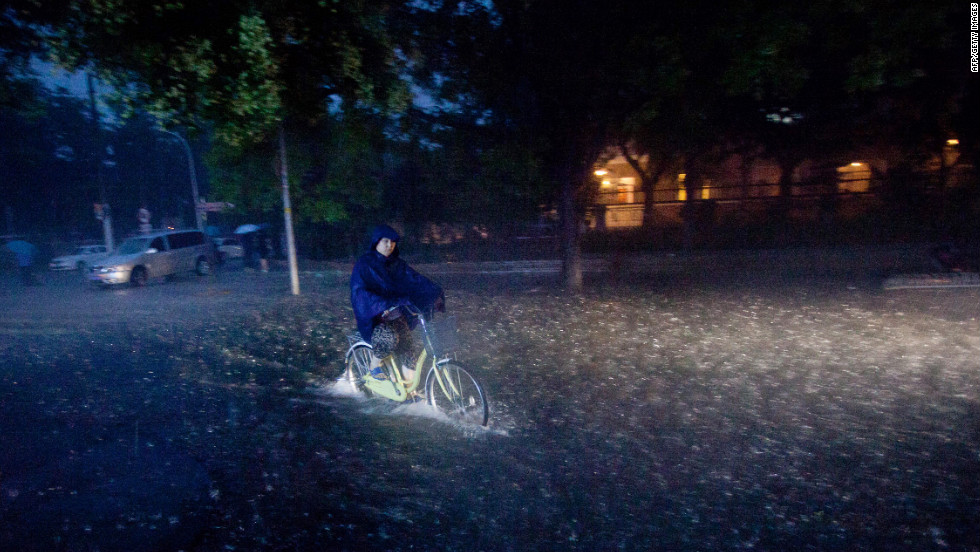 A cyclist rides through a flooded street in Beijing during heavy rainfall Saturday. More rain is forecast as Beijing cleans up after the weekend downpour.