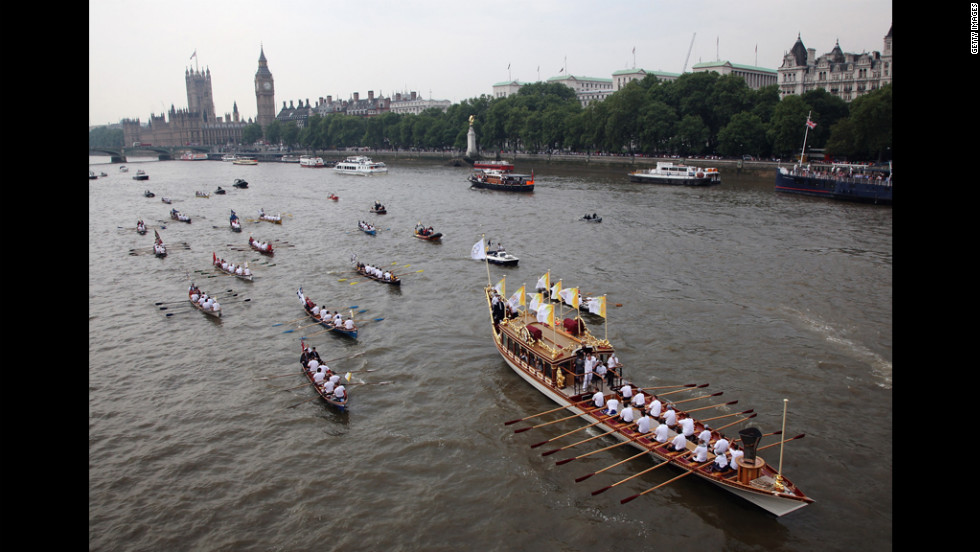The Queen&#39;s royal row barge Gloriana carries the Olympic flame along the River Thames past the Parliament on Friday, July 27, the final day of the torch relay in London. 