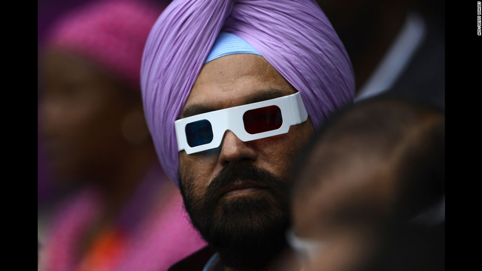 A man wearing glasses waits for the start of the opening ceremony.