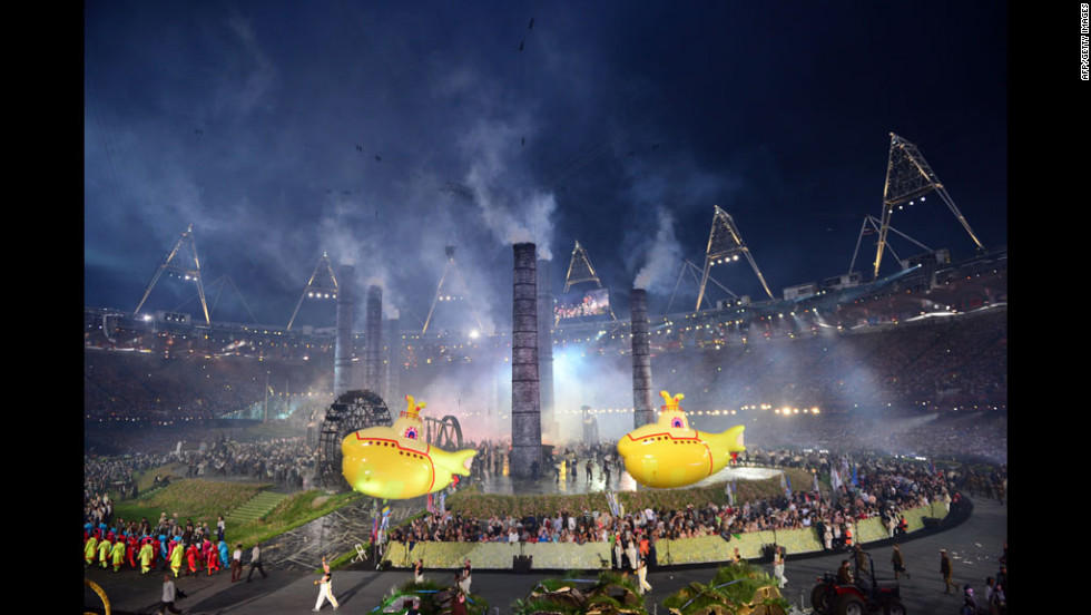 Inflatable yellow submarines float above artists during The Age of Industry scene.