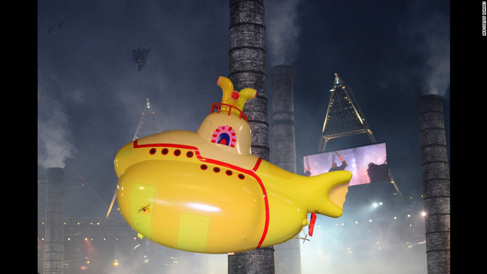 An inflatable yellow submarine floats above artists.