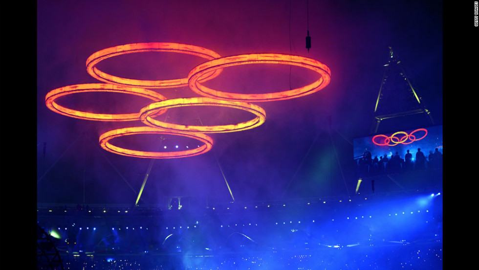 The Olympic rings are assembled above the stadium in a scene depicting the Industrial Revolution.