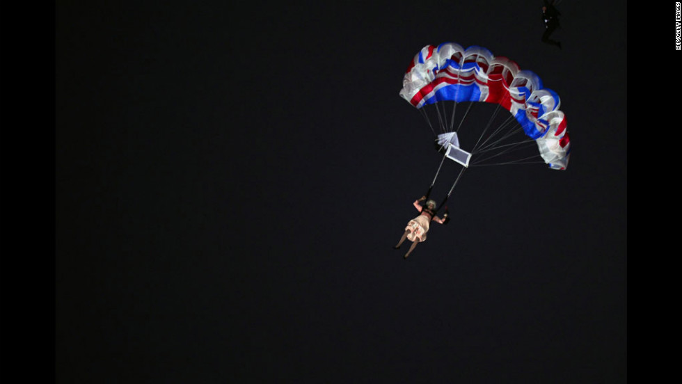 An actor dressed to resemble Britain&#39;s Queen Elizabeth II parachutes into the stadium.