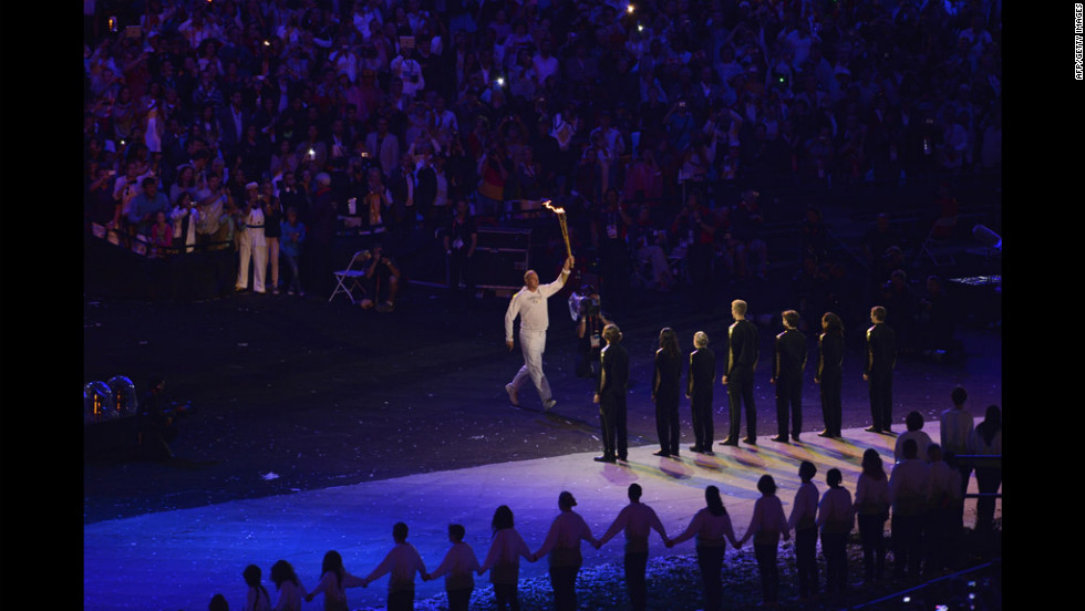 Five-time Olympic rowing gold medalist Steve Redgrave of Britain carries the torch during the opening ceremony and then hands it off to a group of young athletes.  