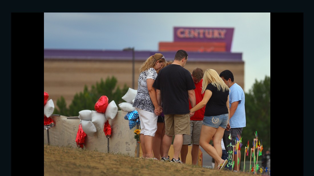 AURORA, CO - JULY 28: Visitors pray together around a cross erected at a memorial setup across the street from the Century 16 movie theatre on July 28, 2012 in Aurora, Colorado. Twenty-four-year-old James Holmes is suspected of killing 12 and injuring 58 others July 20 during a shooting rampage at a screening of &#39;The Dark Knight Rises&#39; in Aurora, Colorado.(Photo by Joe Raedle/Getty Images)