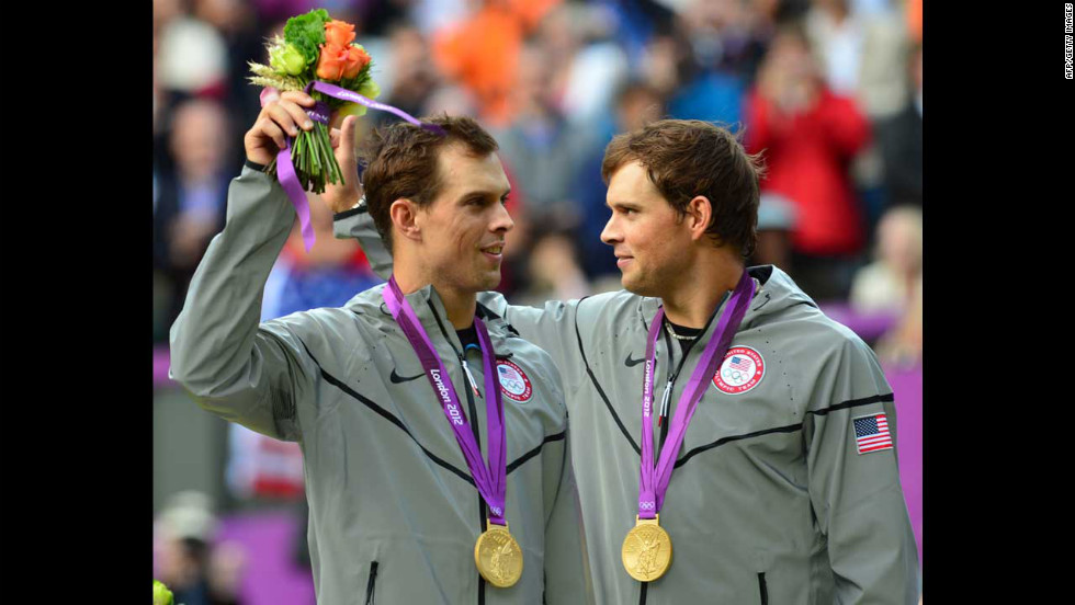 Mike Bryan, left, and Bob Bryan pose on a podium with their gold medals after winning the men&#39;s doubles tennis tournament.