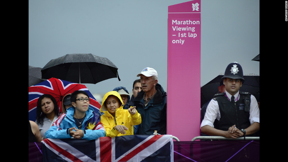 Spectators view the course as rain falls during the women&#39;s marathon race.