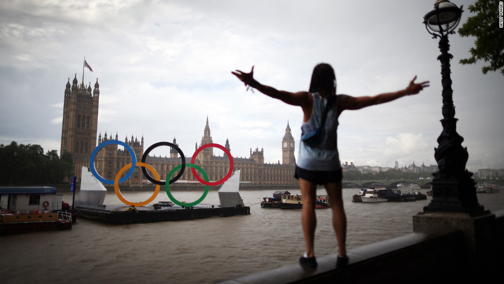 A tourist enjoys the view of giant Olympic rings floating in the River Thames opposite Parliament on Sunday, August 5, in London, England.