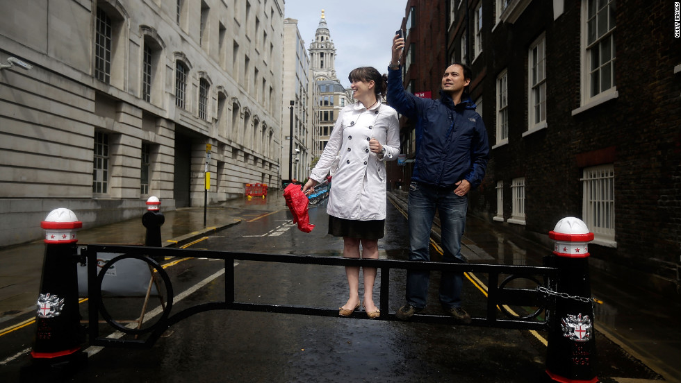 Despite the rain, two spectators eagerly await a view of runners in the women&#39;s marathon near St. Paul&#39;s Cathedral in London.