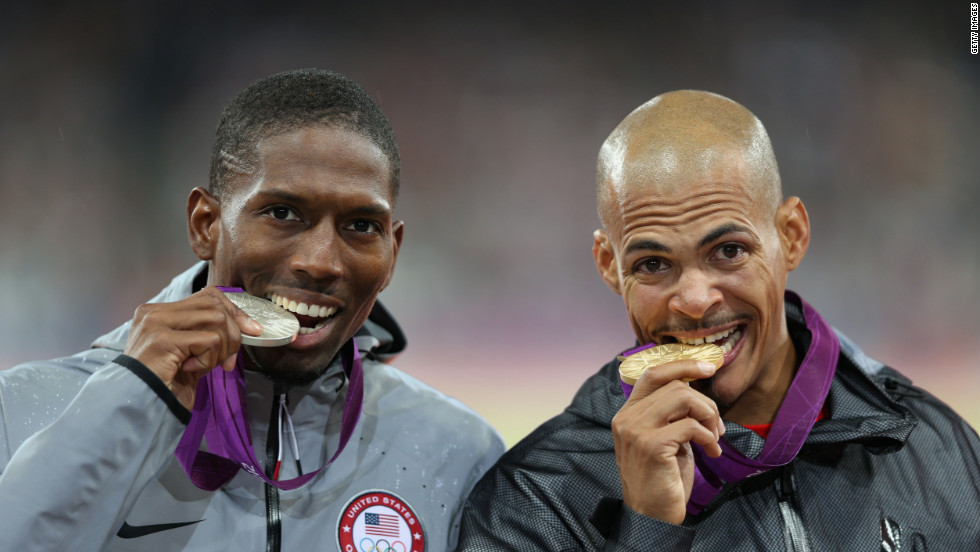 Silver medalist Michael Tinsley of the United States and gold medalist Felix Sanchez of Dominican Republic bite their medals after the men&#39;s 400-meter hurdles final.