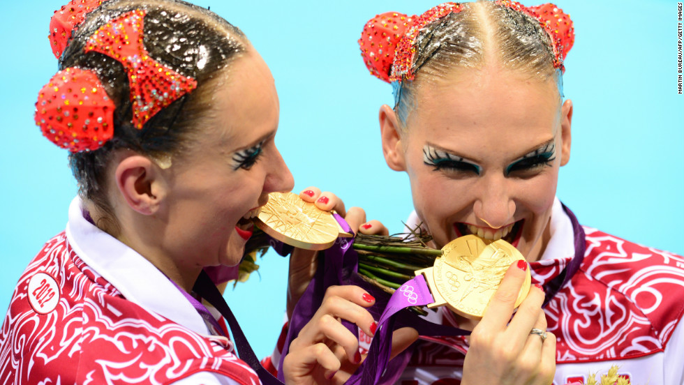 Russia&#39;s Natalia Ishchenko and Svetlana Romashina bite their medals after winning gold in the duets free routine final during the synchronized swimming competition at the London 2012 Olympic Games.