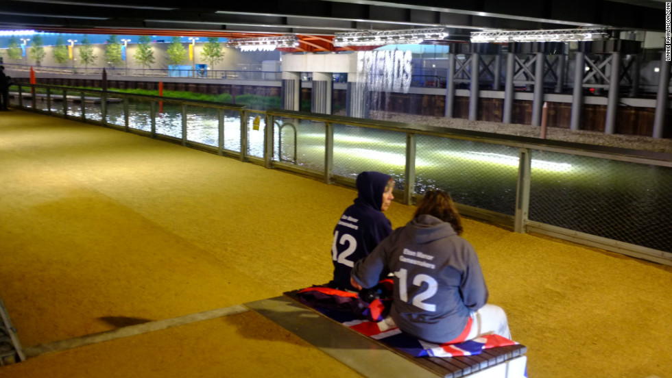 Two Eton Manor volunteers took a moment for a quiet conversation in front of the &quot;bit.fall&quot; installation by artist Julius Popp. Words taken from live news headlines are projected at random onto five man-made waterfalls under the Stratford Gate bridge.