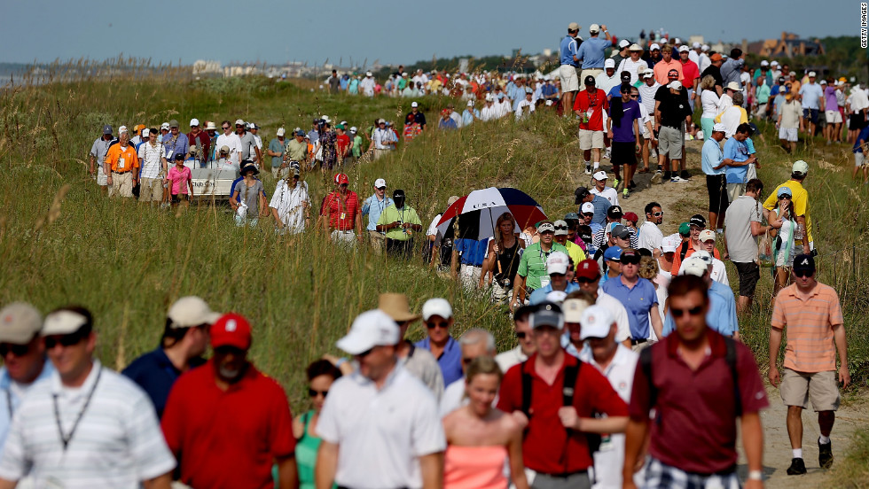 Spectators file along the course near the 16th hole to stake out a position for viewing.