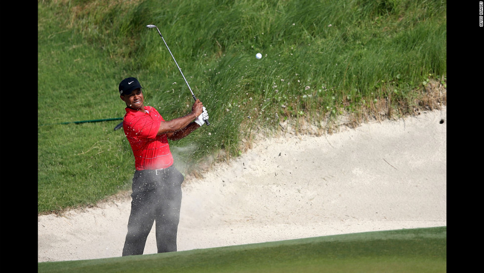 Woods tries to reach the green from a bunker on the 17th hole.