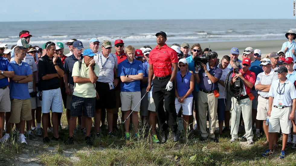 Surrounded by the gallery, Woods jumps to see his ball after his shot on the15th hole.