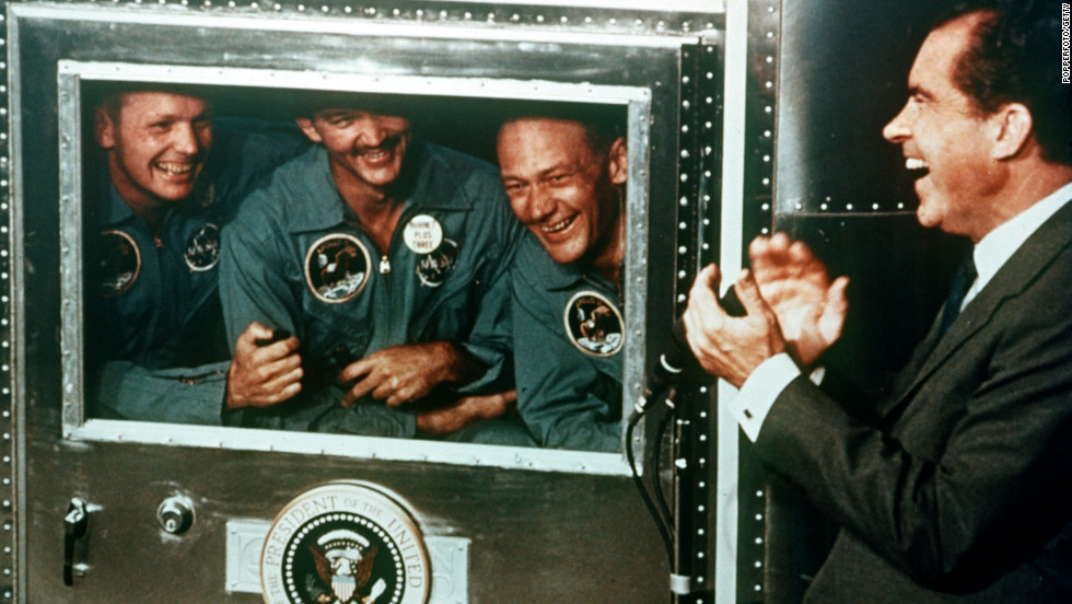 President Richard Nixon applauds the Apollo 11 astronauts, who were confined in a quarantine trailer after their flight, on July 25, 1969.