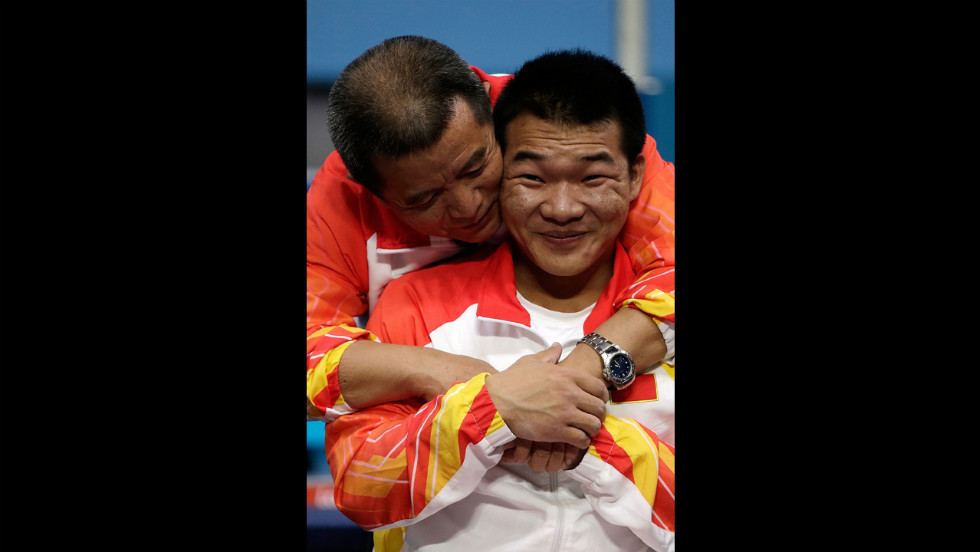 Chinese Qi Feng is congratulated by his coach Weipo Li for his gold during the medal ceremony of the Men&#39;s -52 kg powerlifting.