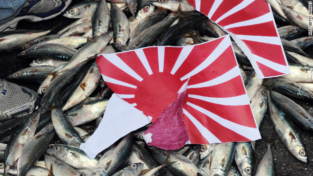 Un desgarrado japonés & # 39; Rising Sun & # 39; Se coloca una bandera sobre peces muertos durante una manifestación en Taipei el 14 de septiembre de 2010, sobre la disputada cadena de islas Senkaku / Diaoyu.