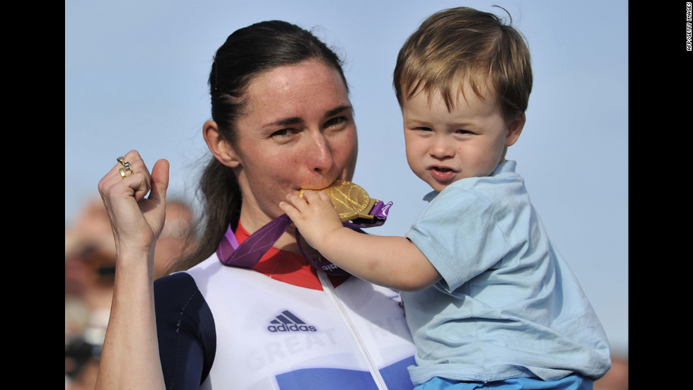 Britain&#39;s Sarah Storey, left, bites her gold medal as her nephew Gethin Crayford holds it on the podium after she won the women&#39;s individual C4-5 road race cycling final on Thursday.