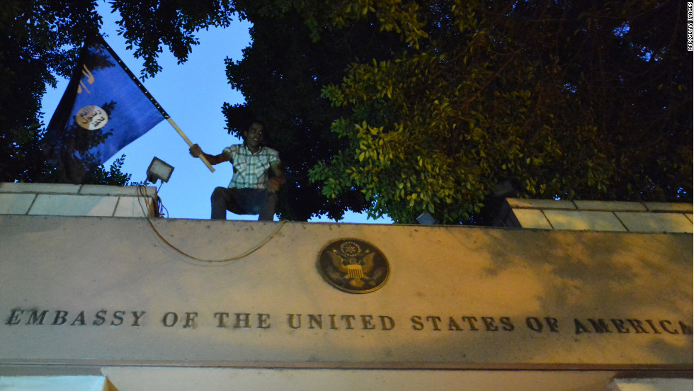 An Egyptian protester waves a black flag inscribed with the Muslim profession of faith -- &quot;There is no God but God, and Mohammed is the prophet of God&quot; -- as he stands above the door of the U.S. Embassy.