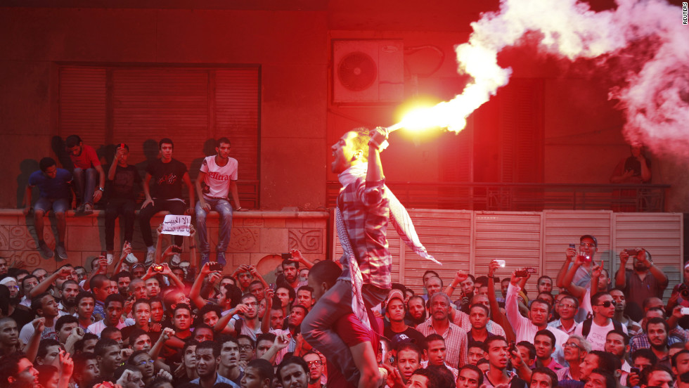 People shout and light flares in front of the U.S. Embassy in Cairo.