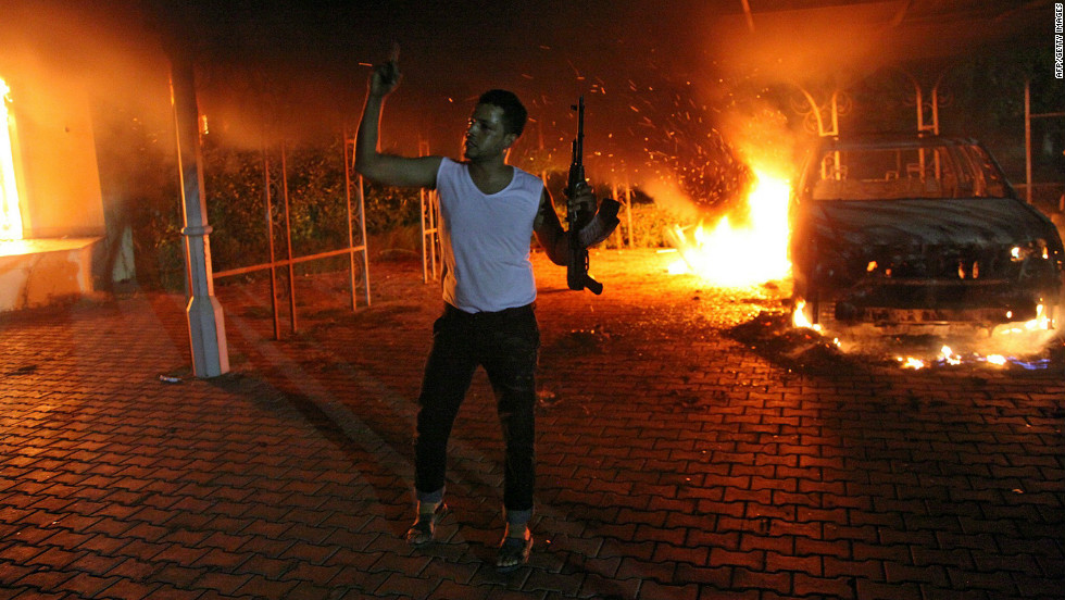 A man waves his rifle as buildings and cars are engulfed in flames inside the U.S. Consulate compound in Benghazi, Libya, late on Tuesday, September 11.