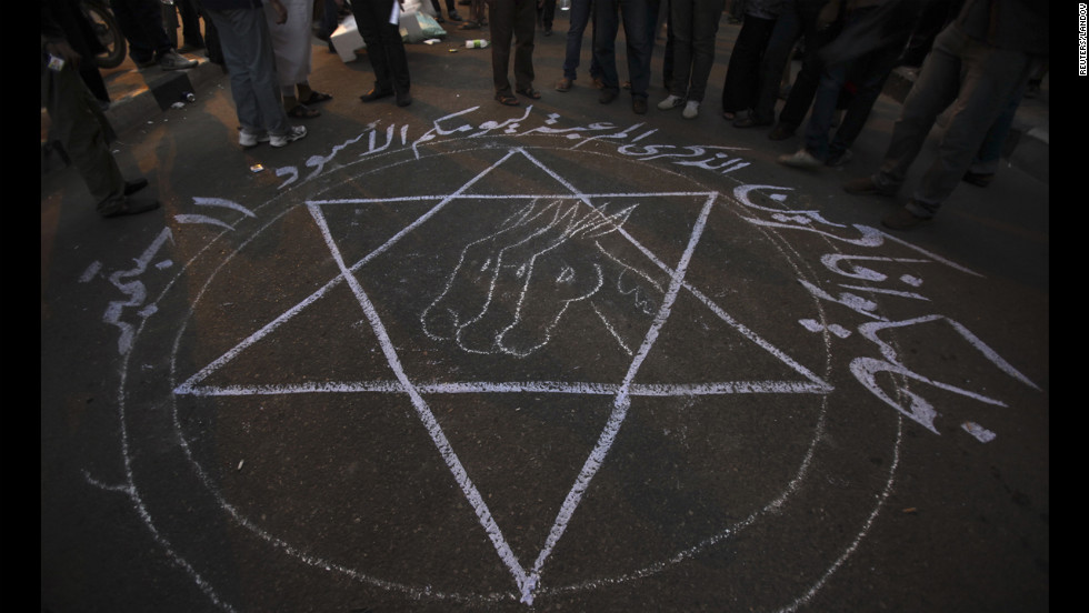 People stand around a drawing that says &quot;Remember your black day 11 September&quot; during the protest in Cairo.