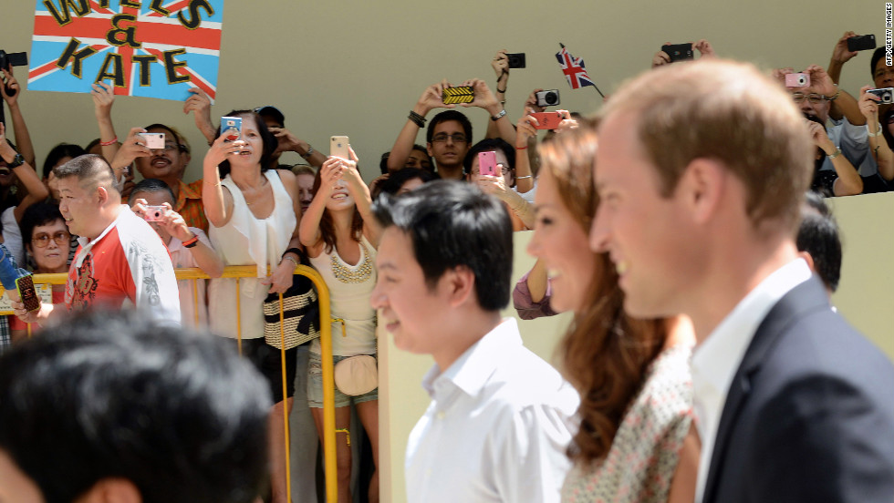 Bystanders crane for photos of the Duke and Duchess of Cambridge during their visit to Strathmore Green, a precinct in Queenstown, a residential district of Singapore on Wednesday.