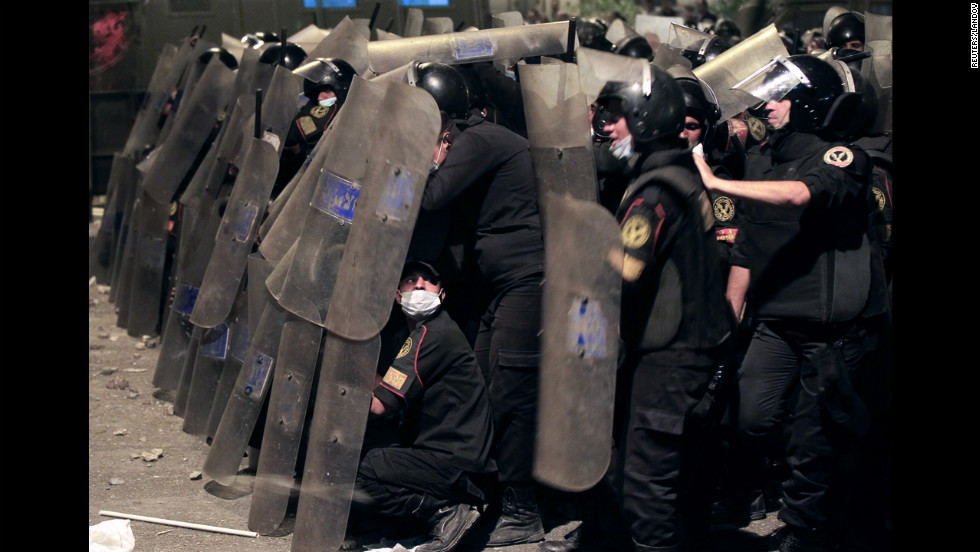  Riot police take cover from stones thrown by protesters on Thursday.