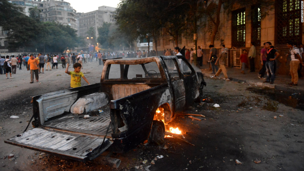 A burned-out pickup sits between Egyptian protesters and riot police in Cairo on Thursday.