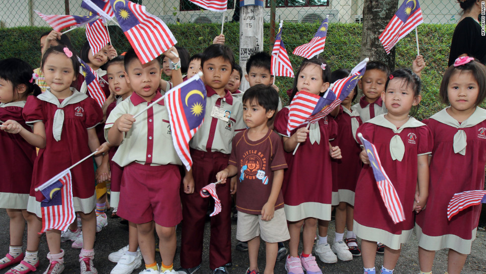 Schoolchildren wave Malaysia national flags as Britain&#39;s Prince William and his wife Catherine, the Duchess of Cambridge, arrive at the Hospis Malaysia in Kuala Lumpur on September 13, 2012.